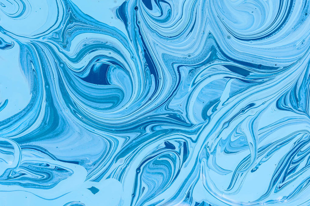The mixing of the two liquid paints dark blue and light blue colors. Beautiful abstract two-color background. Coloring acrylic latex paint - Foto, immagini