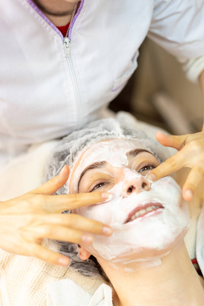 Mujer joven feliz recibe un tratamiento facial en el centro de spa
 - Foto, Imagen