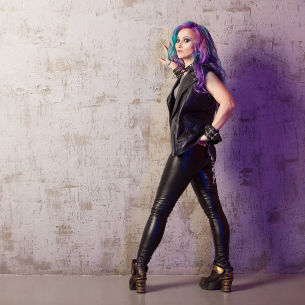 Daring rebel rocker, in black leather clothes with colored hair. Young stylish woman with trendy gradient toning hair - 写真・画像