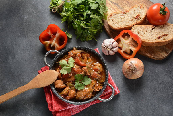 Chakhokhbili - traditional Georgian dish. Chicken stewed with fresh coriander tomatoes and herbs served with a bottle of Georgian wine  - Foto, afbeelding