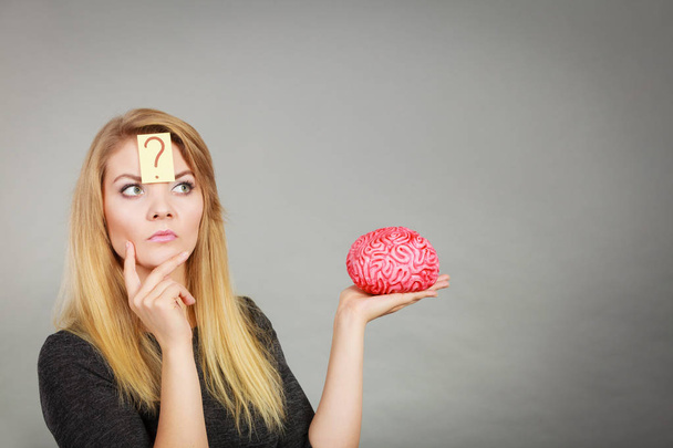 Mujer pensando y sosteniendo cerebro falso
 - Foto, Imagen