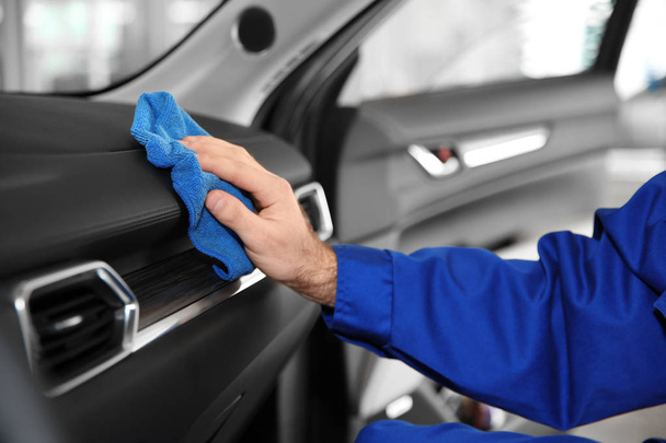 Worker cleaning automobile dashboard with rag at car wash, closeup - Foto, imagen