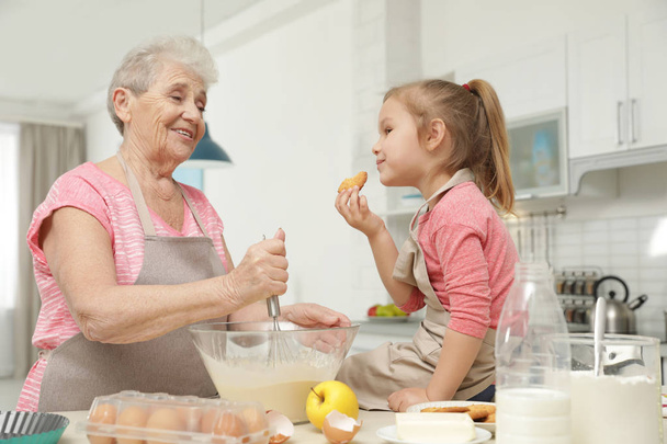 Cute girl and her grandmother cooking in kitchen - Foto, Bild