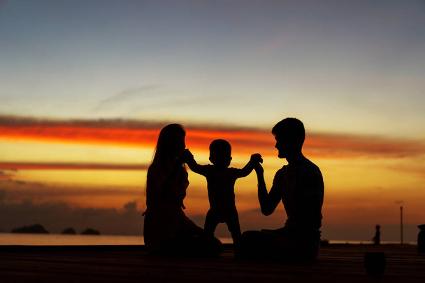 日没時に抱き合う息子と恋する家族、シルエット - 写真・画像