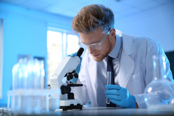 Científico masculino usando microscopio moderno en laboratorio de química
 - Foto, Imagen