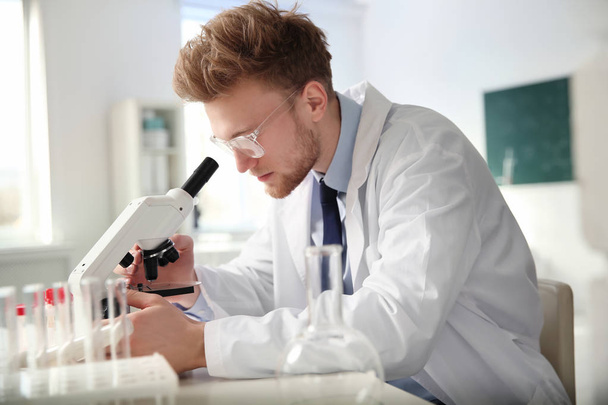 Male scientist using modern microscope in chemistry laboratory - Valokuva, kuva