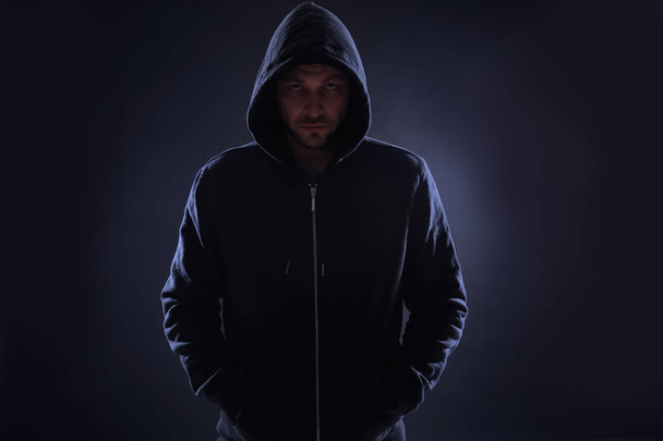 Mysterious man in hoodie on dark background. Dangerous criminal - Foto, imagen