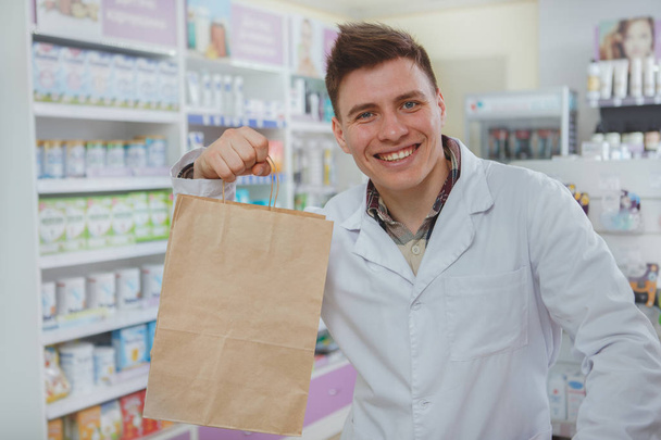 Красивий чоловічий фармацевт працює у своїй аптеці
 - Фото, зображення