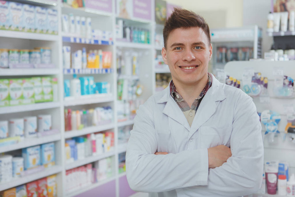 Красивий чоловічий фармацевт працює у своїй аптеці
 - Фото, зображення