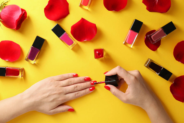 Woman applying bright nail polish on color background, top view - Fotografie, Obrázek