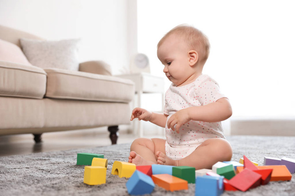 Cute baby girl playing with building blocks in room - Fotoğraf, Görsel