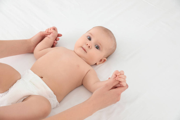 Mother and her cute child on white bed, space for text. Baby massage and exercises - Foto, Bild