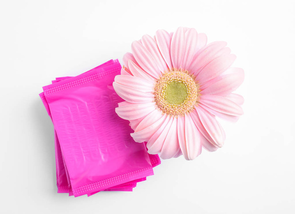 Stack of menstrual pads and gerbera flower on white background, top view. Gynecological care - Foto, Bild