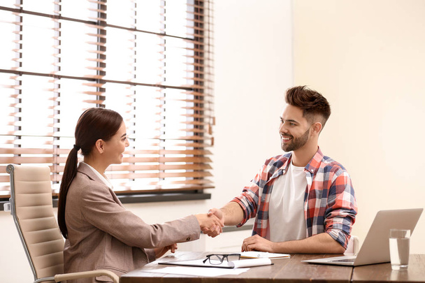 Female insurance agent shaking hands with client in office - Foto, immagini