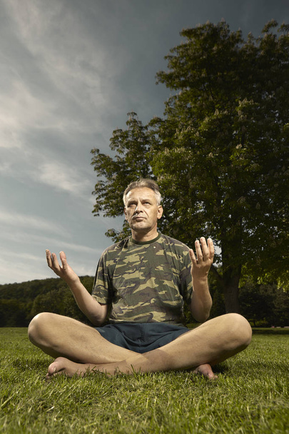 Older man practicing meditation rituals in summer city park - Фото, изображение