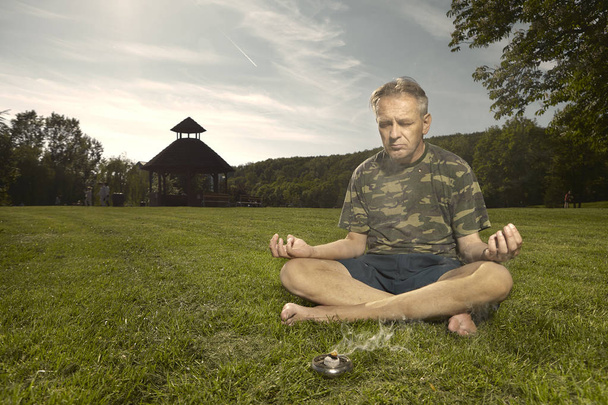 Older man practicing meditation rituals in summer city park - Фото, изображение