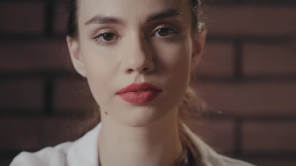 Sexy žena s červenými rty posílání polibek z ruky do kamery na cihlovém pozadí - Záběry, video