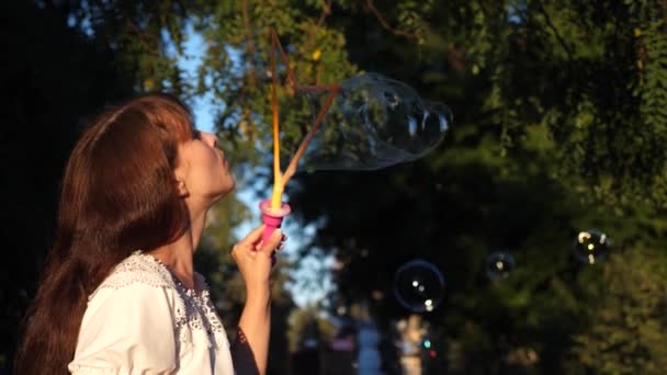 Girl lets big bubbles in city park and smiling. Slow motion - Footage, Video