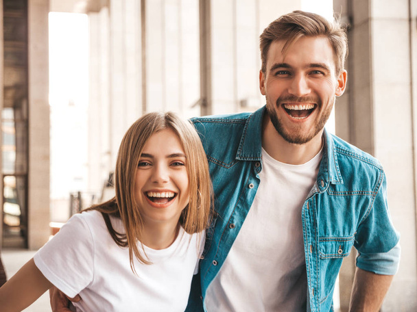 Portrait of smiling beautiful girl and her handsome boyfriend. Woman in casual summer jeans clothes. Happy cheerful family. Female having fun on the street background.Looking at each other - Foto, afbeelding