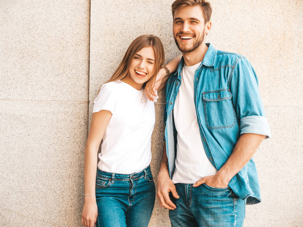 Portrait of smiling beautiful girl and her handsome boyfriend. Woman in casual summer jeans clothes. Happy cheerful family. Female having fun on the street background.Looking at each other - Zdjęcie, obraz