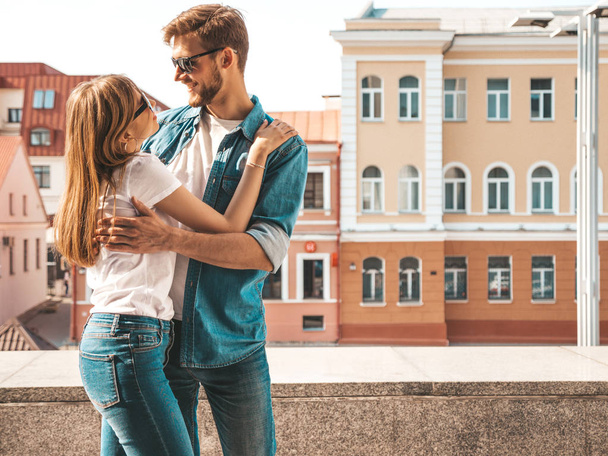 Smiling beautiful girl and her handsome boyfriend. Woman in casual summer jeans clothes. Happy cheerful family. Female having fun on the street background in sunglasses.Looking at each other - Фото, изображение