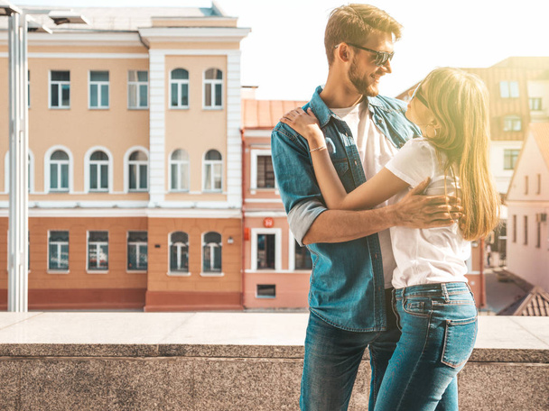 Smiling beautiful girl and her handsome boyfriend. Woman in casual summer jeans clothes. Happy cheerful family. Female having fun on the street background in sunglasses.Looking at each other - Fotó, kép