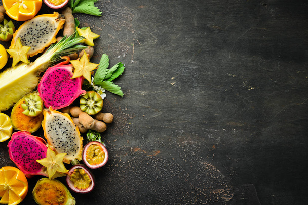 Tropical fruits - passion fruit, pineapple, dragon fruit, kiwi and cactus on a brown background. Top view. - Fotó, kép