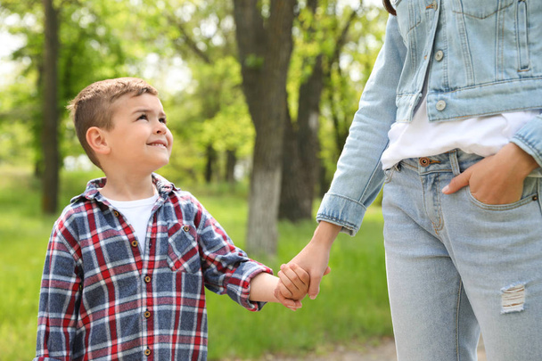 Cute little child holding hands with his mother outdoors. Family weekend - Foto, Imagem