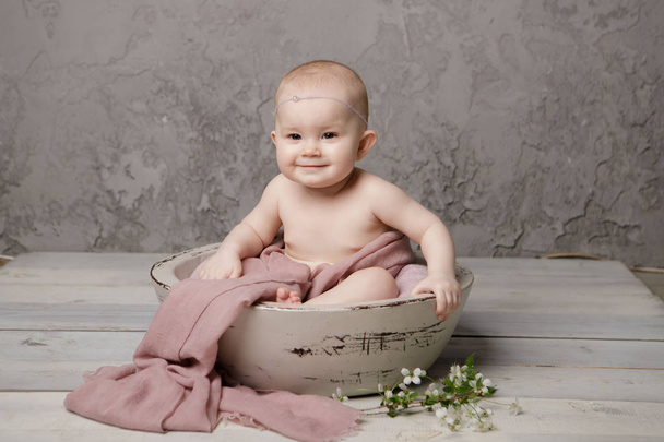 Cute tiny newborn baby princess in a basket, happily smiling and looking at camera, isolated studio shot - Photo, Image