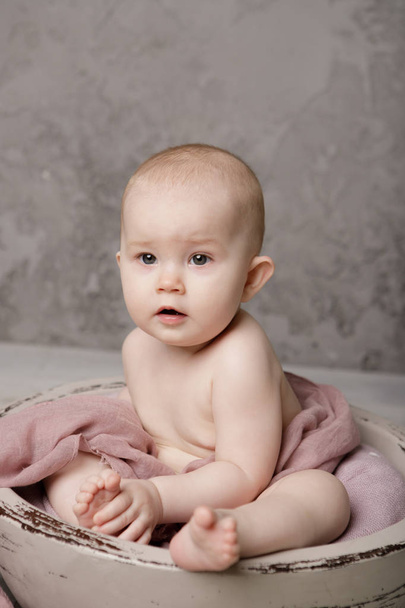 Χαριτωμένο μικροσκοπικό νεογέννητο μωρό πριγκίπισσα σε ένα καλάθι, χαρούμενο χαμόγελο και κοιτάζοντας την κάμερα, απομονωμένη στούντιο shot - Φωτογραφία, εικόνα