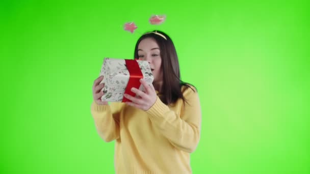 Receiving a gift girl with funny hat rejoices on a green screen - Imágenes, Vídeo