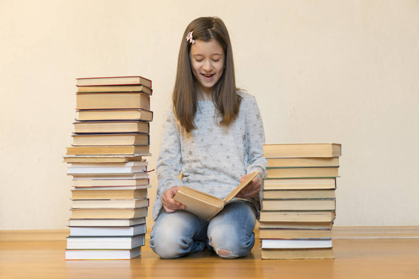 Κορίτσι που διαβάζει ένα βιβλίο που κάθεται στο πάτωμα σε ένα διαμέρισμα. Χαριτωμένο κορίτσι διαβάζει το βιβλίο στο σπίτι. εκπαίδευση και το σχολείο ιδέα-μικρό μαθητή κορίτσι κάθεται στο πάτωμα και διαβάζοντας βιβλίο - Φωτογραφία, εικόνα