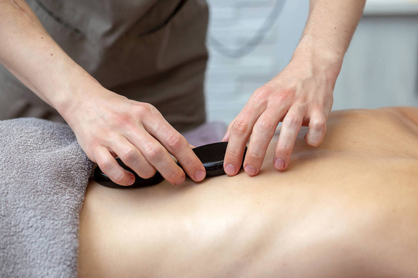 A woman is getting a hot stone massage at a spa - Foto, immagini