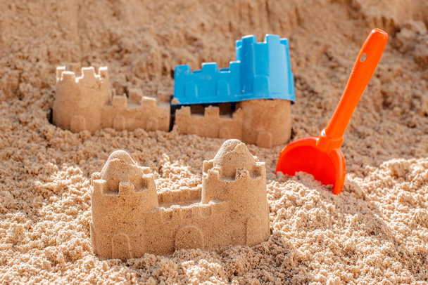 Детские игрушки для строительства песчаного замка, лопаты, плесени, лежащие на песке на берегу моря
, - Фото, изображение