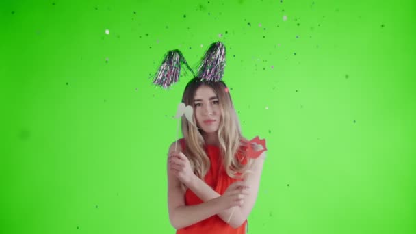 Beautiful girl in party hat are dancing under falling confetti and Balloons on a green screen . - Video, Çekim