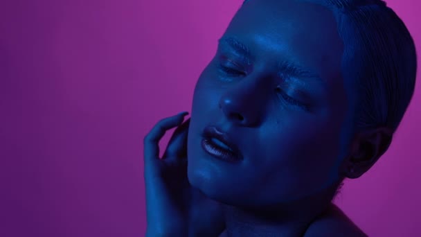 Όμορφο θηλυκό μοντέλο που ποζάρει σε μπλε και ροζ φως νέον στο στούντιο - Πλάνα, βίντεο