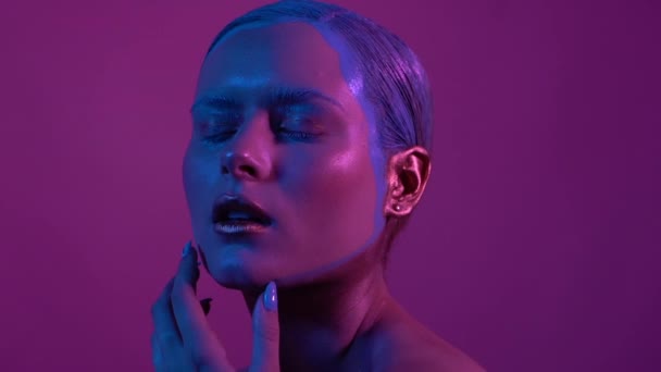 Hermosa modelo femenina posando en luz de neón azul y rosa en el estudio
 - Metraje, vídeo
