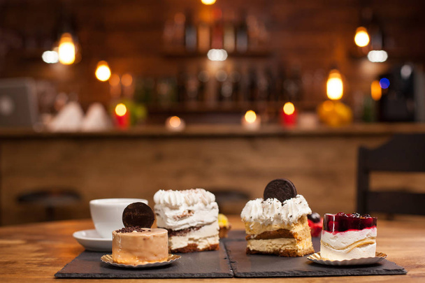 Diferentes pasteles con crema de pudín en una mesa de madera en una cafetería
 - Foto, imagen