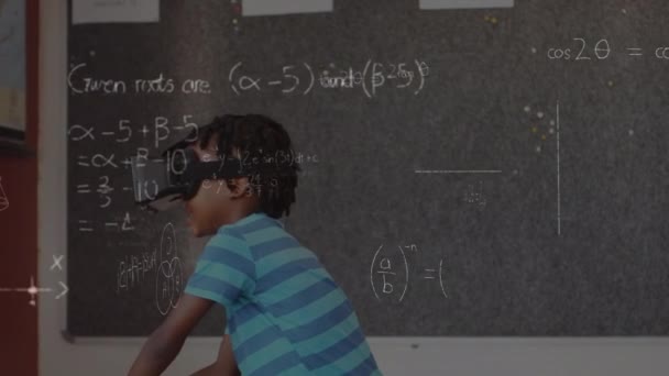 Digital composite of an African-american boy wearing a virtual reality headset in front of the class with graphs and equations in the foreground - Záběry, video