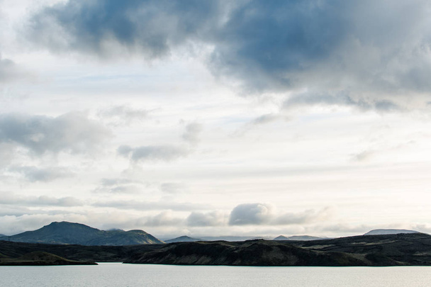 Vista fantástica da Islândia na primavera. Crepúsculo brilhante de primeiras noites brancas sobre as paisagens sonhadoras com água azul do lago e montanhas nebulosas verdes. Vista esplêndida da casa do lago
 - Foto, Imagem