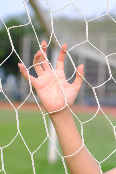 Hand hold on net of soccer goal. - Фото, изображение