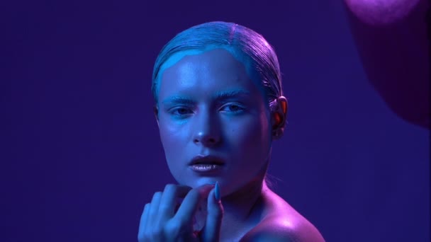 Beautiful female model posing in blue and pink neon light in studio - Materiaali, video