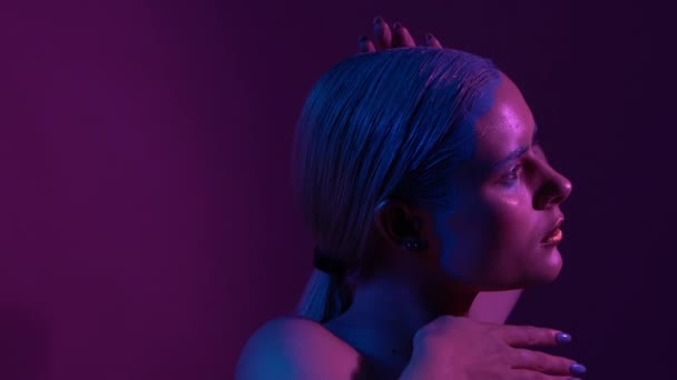 Beautiful female model posing in blue and pink neon light in studio - Záběry, video