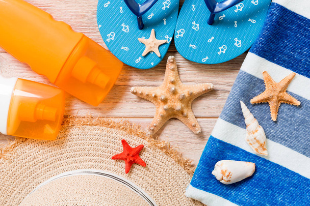 フリップフロップ、麦わら帽子、ヒトデ、日焼け止めボトル、木製の背景トップビューにボディローションスプレー。フラットレイ夏のビーチ海のアクセサリーの背景、旅行のコンセプト - 写真・画像