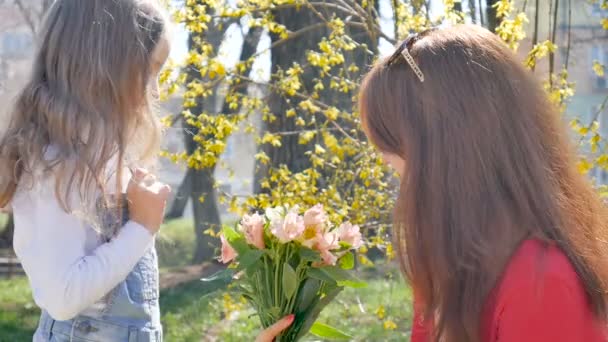 Young sensual mother looking at pretty beautiful bouquet of colorful flowers spending time together outdoors in the park. Happy mothers day - Záběry, video