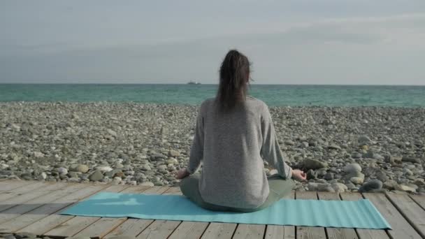 Брюнетка жінка медитації на березі моря. - Кадри, відео