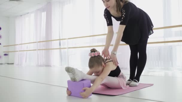 Вчитель балету професійна балерина допомагає дівчині розтягувати ноги
 - Кадри, відео