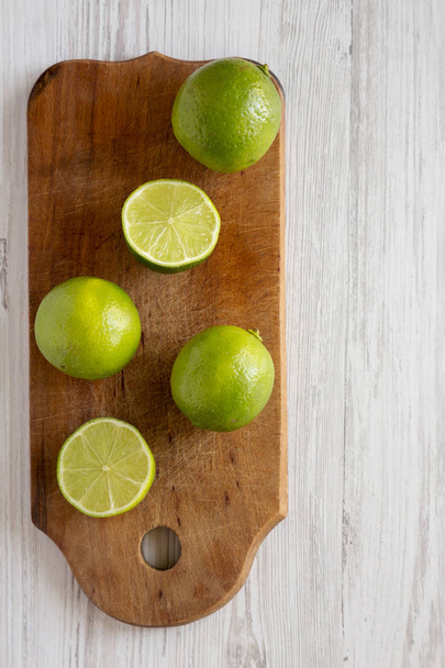 Limes di agrumi verdi interi e tagliati su una tavola di legno rustica sopra w
 - Foto, immagini