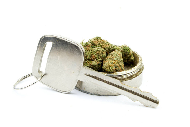 Закройте вид на высушенную марихуану, ключ и мотылька на белом фоне
 - Фото, изображение