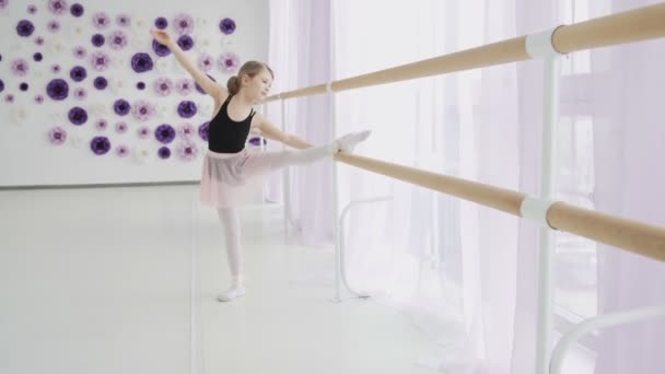 Little girls using ballet barre when doing leg stretching exercises in dance studio - Video, Çekim
